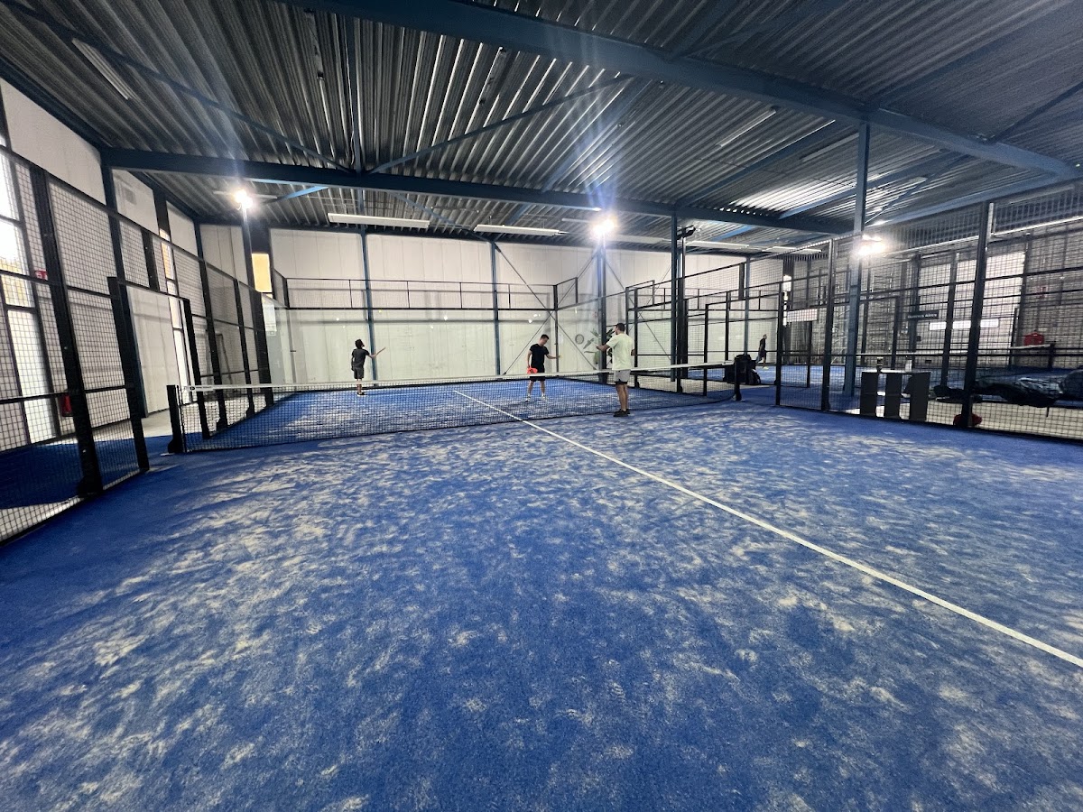 Binnen padelclub met blauwe hardcourt, zwarte netting en LED-verlichting